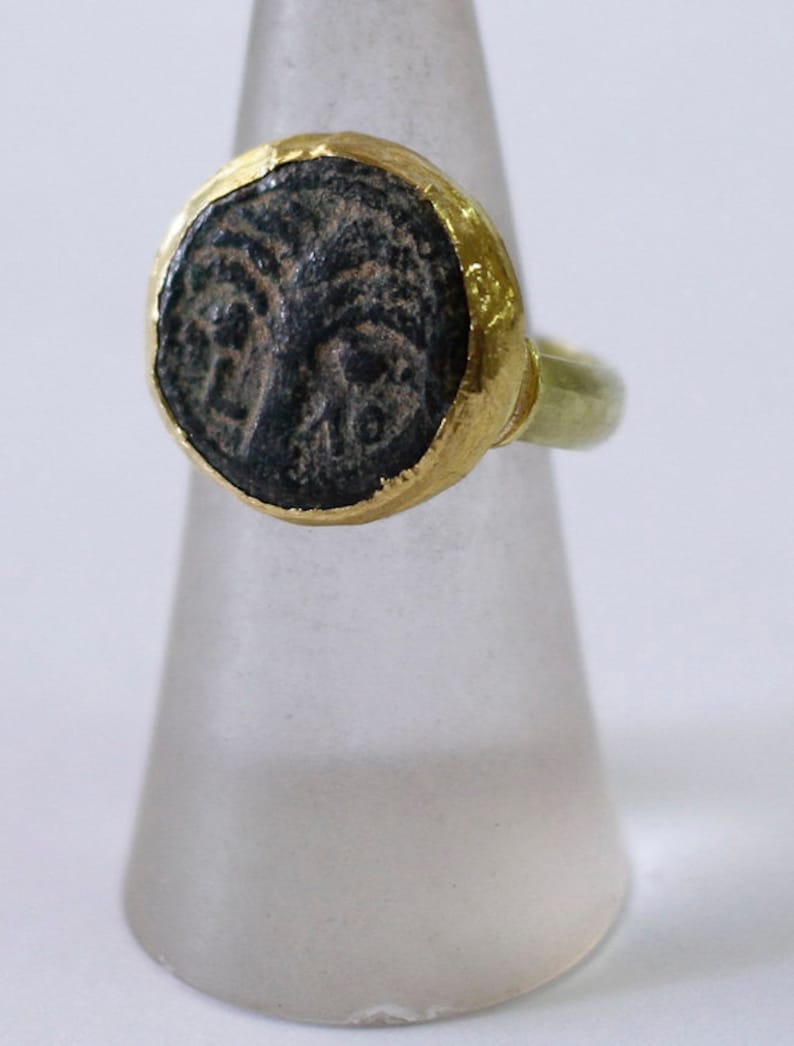 May include: A gold ring with a black stone featuring a detailed design. The stone is set in a gold bezel and the band is a simple gold band.