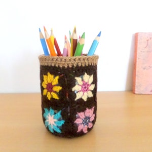 かぎ針編みの鉛筆ポット、茶色の背景に小さな色とりどりの花