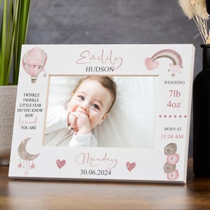 May include: White picture frame with a baby photo, featuring a pink hot air balloon, rainbow, and moon illustrations. Text includes the baby's name, birth details, and the phrase "Twinkle Twinkle Little Star".