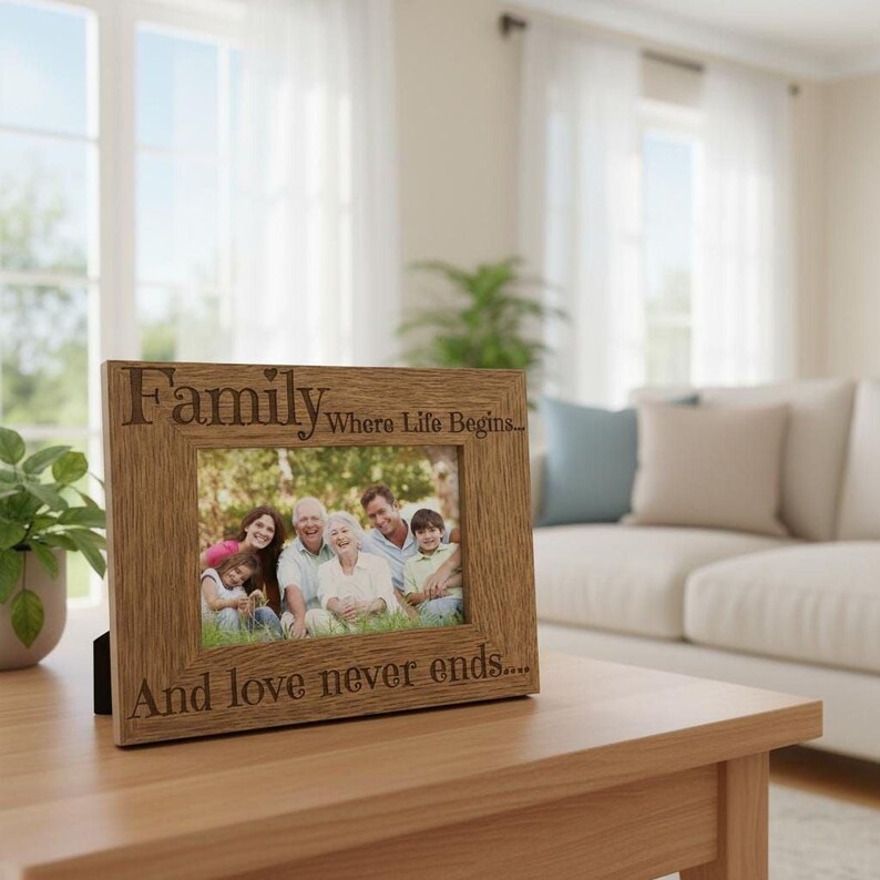 A wooden picture frame with a family photo inside sits on a wooden table in a living room, with a couch and potted plant visible in the background.
