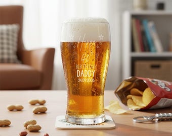 May include: A tall beer glass filled with golden beer and a foamy head. The glass is etched with the words "Happy 40th Birthday Daddy 24.09.2006". Peanuts, potato chips, and a bottle opener are on the table.