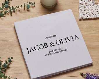 May include: A white wedding photo album with the text "Wedding Day Jacob & Olivia 22nd May 2022 Somerset House London" printed on the front cover.
