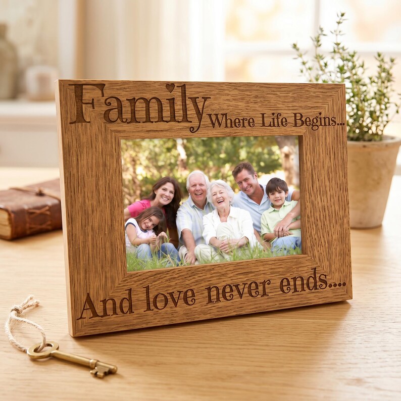 A wooden picture frame with a family photo inside, placed on a wooden surface next to a key and a potted plant.