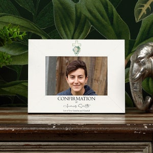 May include: White picture frame with a cross and floral design. The frame says "Confirmation of James Smith" and "Lots of love Grandma and Grandad".