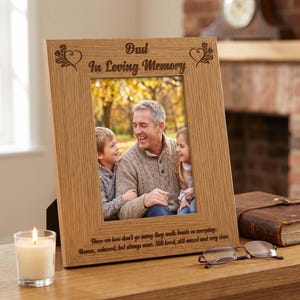 A wooden picture frame with a photograph of a man and two children, accompanied by a candle and a book on a wooden shelf.