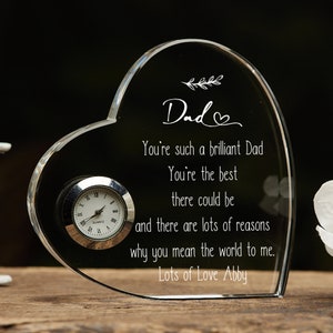 May include: A clear heart-shaped crystal paperweight with a small clock embedded in the side. The paperweight has an engraved message that reads "Dad You're such a brilliant Dad You're the best there could be and there are lots of reasons why you mean the world to me. Lots of Love Abby".