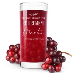 May include: A glass of red juice with the text "Congratulations on your Retirement Martin Love from the team" on the side. There are red grapes next to the glass.