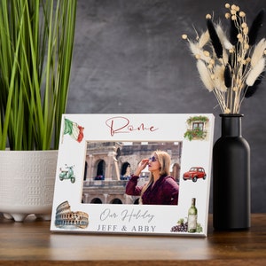 Puede incluir: Marco de fotos blanco con una foto de una mujer frente al Coliseo en Roma. El marco tiene una bandera italiana roja y verde, un coche rojo, una scooter verde, una botella de vino y uvas. El texto "Roma" está escrito en rojo cursivo en la parte superior del marco. El texto "Our Holiday JEFF & ABBY" está escrito en rojo en la parte inferior del marco.