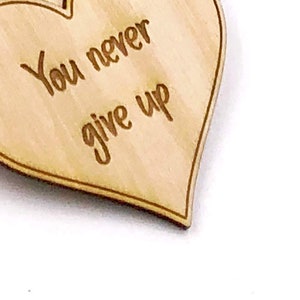 May include: Wooden heart-shaped ornament with the text "You never give up" engraved on it.