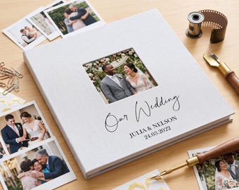 May include: A white wedding photo album with a framed photo of a couple. The album cover reads "Our Wedding" with the names Julia & Nelson and the date 24.03.2022. Additional photos, film reel, and tools are scattered around.