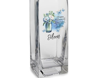 May include: A clear glass vase with a square base. The vase features a floral design with butterflies and the text "Happy Retirement May you be proud of the work you have done. The journey you are on. The difference you have made." and the name "Eileen".