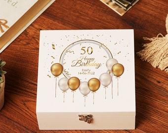 Puede incluir: Caja de madera blanca con un diseño dorado de globos y confeti. El texto en la caja dice "50 Feliz Cumpleaños Emily 14-06-2022".