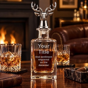 May include: A clear glass decanter filled with amber liquid, featuring a silver-coloured stag head stopper. The front of the decanter is engraved with the text Your Title and sentiment engraved on the decanter in a clean, sans-serif font.