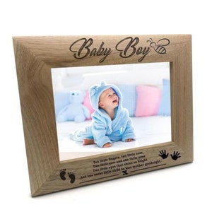 May include: A light brown wooden photo frame with a cutout of a bee and the words "Baby Boy" engraved on the top. The frame includes a poem about a baby with the text "Ten little fingers, ten little toes, Two little ears and one little nose Two little eyes that shine so bright And one sweet little child to kiss mother goodnight."