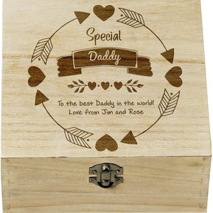 以下が含まれることがあります： ヒンジ付きの蓋とラッチが付いた木製の箱。蓋には「Special Daddy」と「To the best Daddy in the world! Love from Jim and Rose」という文字が刻まれています。彫刻は矢印とハートの円に囲まれています。