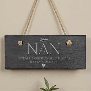 May include: A rectangular black slate sign with the word "NAN" in white, along with the text "LOVE YOU MORE THAN ALL THE STARS" and names. The sign is suspended by a natural rope.