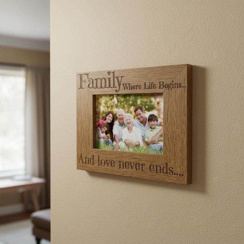 A wooden picture frame with a family photo inside, mounted on a wall. The frame has a message engraved on it that says "Family Where Life Begins... And love never ends..."