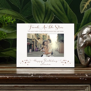 May include: White photo frame with a brown inscription that reads "Friends Are Like Stars You Don't Need To See Them To Know They Are There". The frame has a photo of two women hugging in front of a building. The inscription "Happy Birthday Laura" is below the photo.