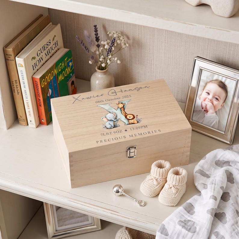 A wooden box with a baby's name and birth date, surrounded by baby items such as a baby's booties, a baby's pacifier, and a framed photo of a baby.
