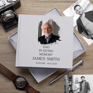 May include: A white photo album with a black and white photo of a man on the cover. The album has the text "Dad In Loving Memory James Smith 15.09.1958 - 16.02.2025" printed on the front.