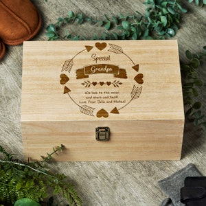May include: A wooden box with a hinged lid and a metal latch. The lid is engraved with the words "Special Grandpa" and a design of hearts and arrows. The text below the design reads "We love to the moon and stars and back! Love from Julia and Michael."