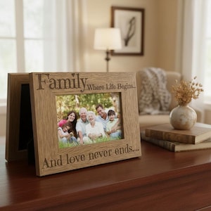 A wooden picture frame with a family photo inside, placed on a wooden surface. The frame has a message that reads "Family Where Life Begins... And love never ends..."