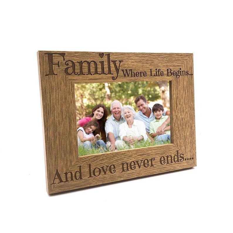 A wooden picture frame with a family photo inside, containing a group of people sitting together in a natural outdoor setting.