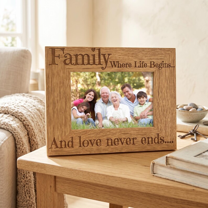 A wooden picture frame with a family photo inside, placed on a wooden table. The frame has a message engraved on it that says "Family Where Life Begins... And love never ends..."