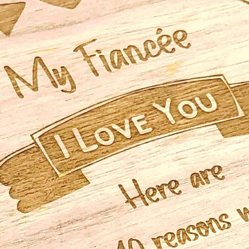 May include: A wooden sign with the text "My Fianc&eacute;e I Love You Here are 40 reasons why" engraved on it.