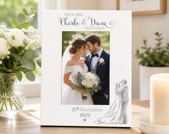 May include: A white rectangular photo frame featuring the text MR & MRS CHARLIE & DIANA RICHARDS at the top and 27th December 2022 at the bottom. The frame displays a photograph of a couple and a black line drawing of a couple embracing.
