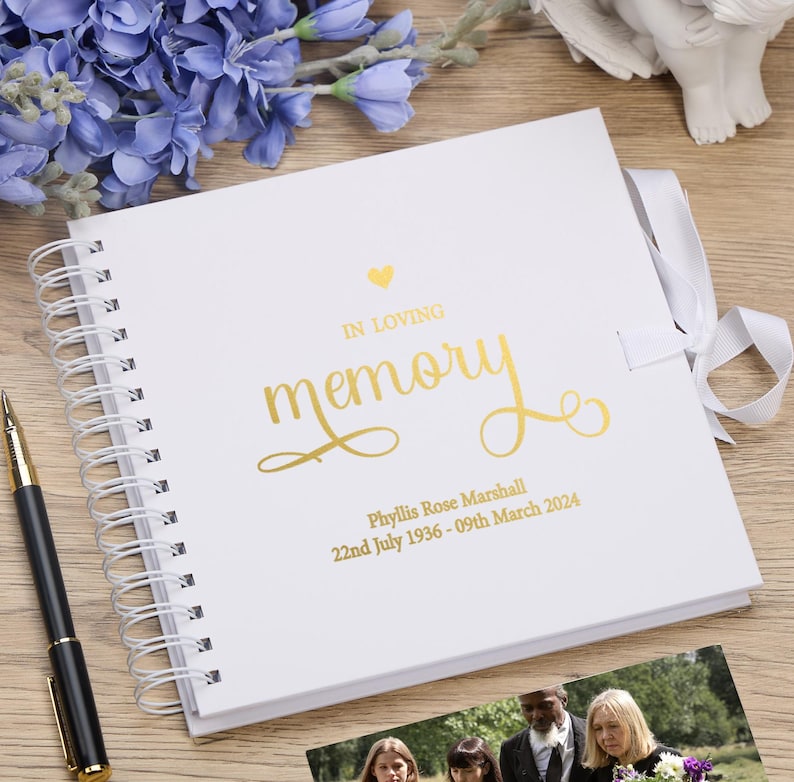 May include: White spiral bound memory book with a gold foil heart and the words "In Loving Memory" in gold foil lettering. The book also includes the name "Phyllis Rose Marshall" and the dates "22nd July 1936 - 09th March 2024" in gold foil lettering.