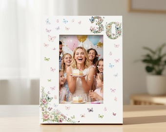 May include: White picture frame decorated with floral and butterfly accents, and the number "30" in floral design. The frame holds a photo of a birthday celebration with a woman holding a cake.
