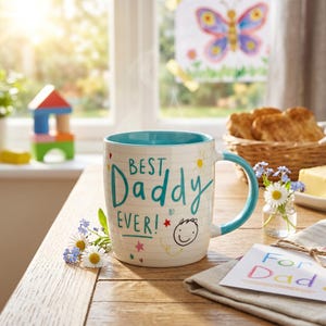 May include: A white ceramic mug with a teal interior and handle, featuring the text "BEST Daddy EVER!" in teal script. The mug has a lined paper pattern, a hand-drawn smiley face, a yellow sun, and small colorful stars and hearts printed on the exterior.