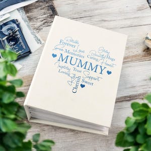 May include: A white photo album with blue text that reads "Giving, Reliable, Forever Love, Fun Memories, Beautiful Hugs, Caring, Honest, MUMMY, Inspiring, Trust, Support, Loving, Kind, Cherish, Sweet". There are small blue hearts around the text.