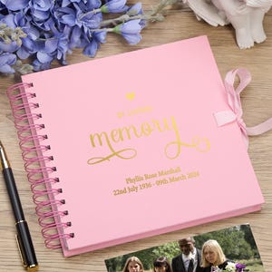 May include: Pink spiral bound memory book with a gold ribbon and the words "In Loving Memory" and "Phyllis Rose Marshall 22nd July 1936 - 09th March 2024" in gold lettering.