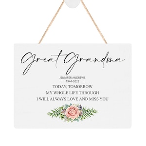 May include: A white rectangular wooden sign with the words "Great Grandma" in elegant black script. The sign includes the name "Jennifer Andrews" and dates "1944-2022", along with a floral arrangement and a rope for hanging.