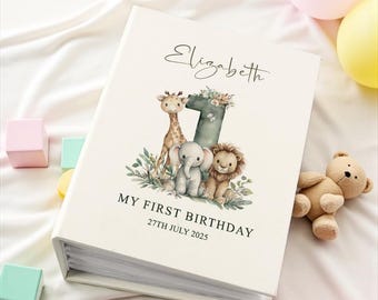 May include: A cream-colored photo album featuring the name Elizabeth, the number 1, and illustrations of a giraffe, elephant, and lion. The text reads My First Birthday and 27th July 2025. The cover is decorated with greenery and floral accents.