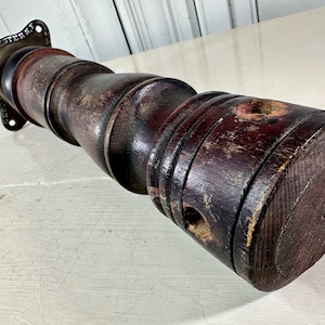 May include: A dark brown wooden post with a metal base that reads "Rochester". The post has a worn, distressed finish and is likely an antique.