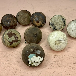 May include: Ten round wooden knobs with various paint finishes, including white, brown, and green. Some knobs have holes and others have markings.