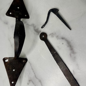 May include: A set of three antique iron door hardware pieces. The main piece is a door handle with a triangular base and a curved handle. The other two pieces are a hook and a long, thin piece of metal.