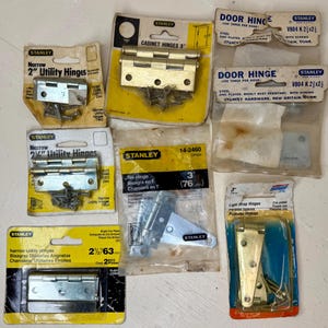 May include: Assortment of Stanley brand hinges in various sizes and styles, including cabinet hinges, door hinges, and utility hinges. Packages are yellow and white, with text indicating measurements in inches.