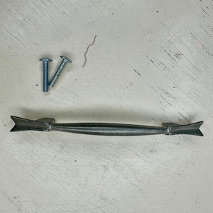 May include: A handmade wooden sign with the text "Welcome" in a handwritten style. The sign is painted white with a distressed finish, and a small green leaf is attached to the top. The sign measures approximately 12 inches wide.