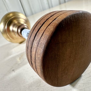 May include: A wooden candle holder with a gold metal base. The holder has a round, flat top with a grooved design.