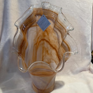 May include: A white and brown glass vase with a wavy, ruffled rim. The vase has a swirl pattern and is approximately 12 inches tall.