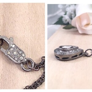 Puede incluir: Un collar de plata con un colgante en forma de l&aacute;grima con un peque&ntilde;o diamante en el centro. El colgante est&aacute; rodeado de diamantes m&aacute;s peque&ntilde;os y la cadena es de plata con un cierre de langosta.
