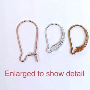 May include: Three earring hooks in different finishes: gold, silver, and rose gold. The hooks are enlarged to show detail.