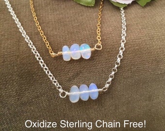 May include: Two silver necklaces with opal beads. The top necklace has a gold chain and the bottom necklace has a silver chain. Both necklaces have three opal beads. The text "Oxidize Sterling Chain Free!" is at the bottom of the image.