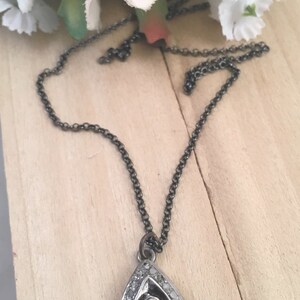 Puede incluir: Un collar con un colgante de plata en forma de l&aacute;grima, adornado con un gran diamante bruto claro en el centro. El colgante est&aacute; rodeado de diamantes m&aacute;s peque&ntilde;os y cuelga de una delicada cadena de plata.