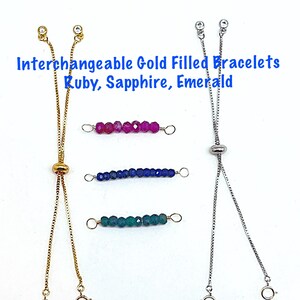 May include: Three gold-filled adjustable bracelets with interchangeable gemstone beads. The bracelets feature a slider clasp and are available in ruby, sapphire, and emerald.