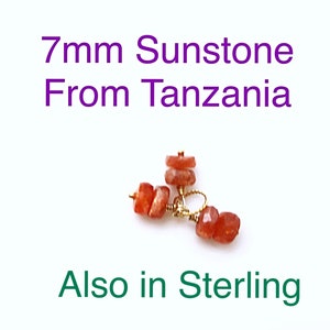 May include: Close-up of a pair of earrings featuring 7mm sunstone beads from Tanzania. The earrings are made with gold wire and have a natural, earthy look.